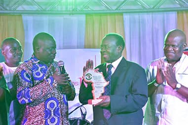 Sembuule (c) recieves his award from Fort Portal MP and PAP patron Alex Ruhunda