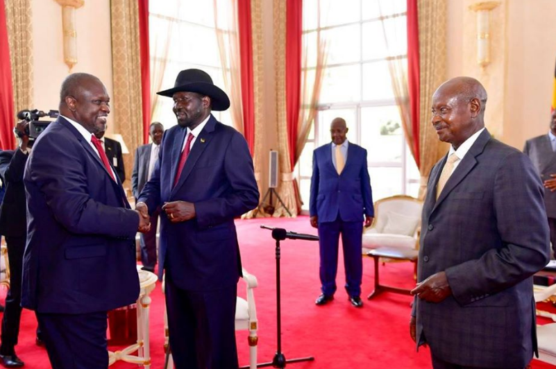 Riek Machar and Salva Kiir shake hands as Museveni looks on